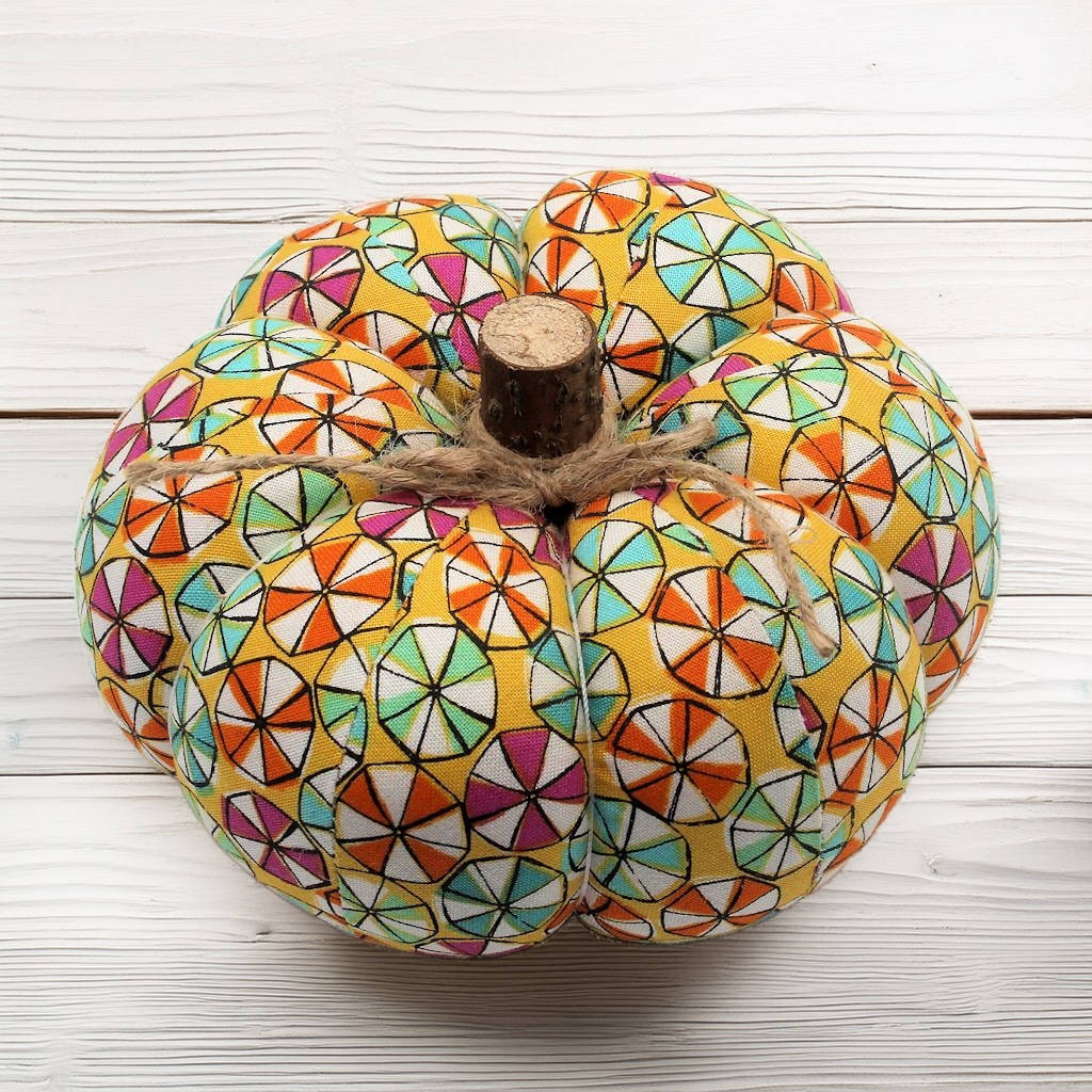 Decorative pumpkin with colorful candy pattern on a white wooden surface