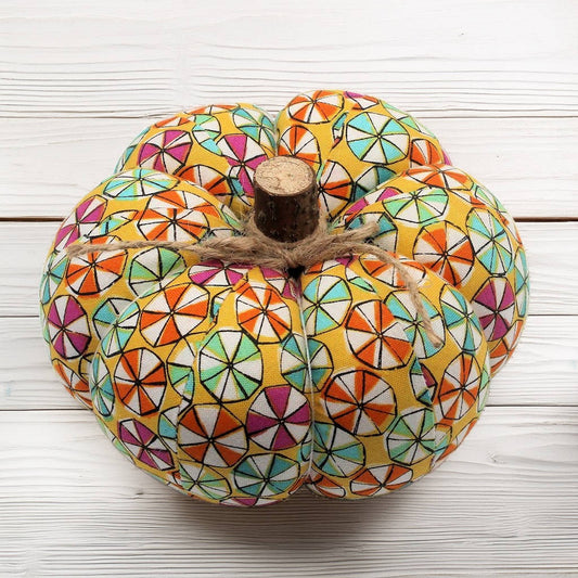 Decorative pumpkin with colorful candy pattern on a white wooden surface