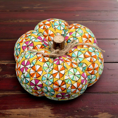 Decorative pumpkin with colorful candy pattern on a white wooden surface