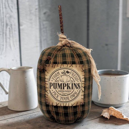 Decorative pumpkin with 'Farm Fresh Pumpkins' label on a wooden surface with mugs in the background.