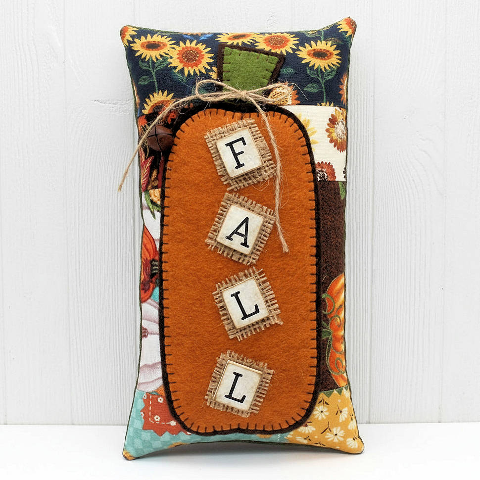 Decorative pillow with 'FALL' text and autumnal patterns on a white background