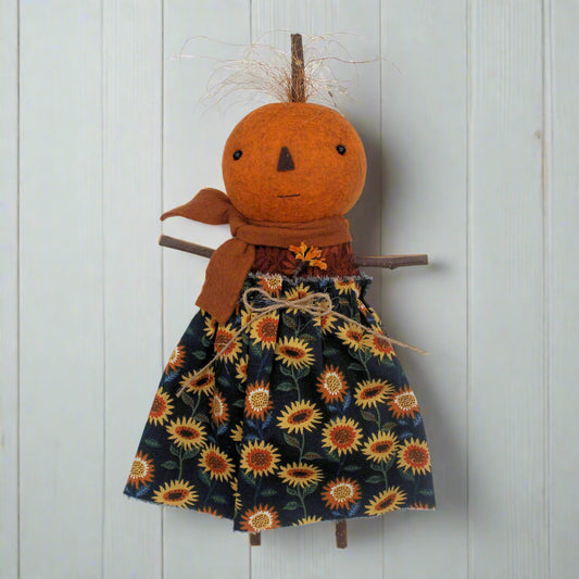Pumpkin character doll with a sunflower dress on a white background