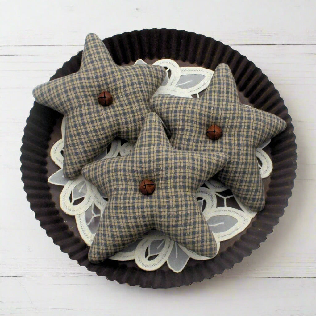 Three colonial blue homespun star bowl fillers with buttons on a decorative plate.