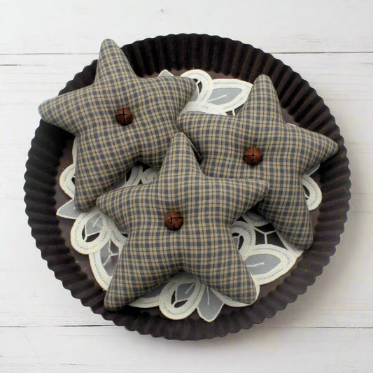 Three colonial blue homespun star bowl fillers with buttons on a decorative plate.