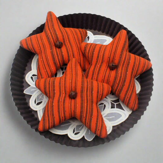 Star-shaped orange fabric bowl fillers with on a decorative plate with a white background