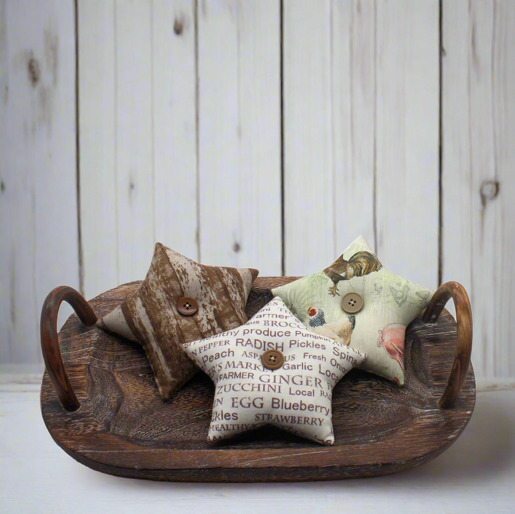 Three decorative farmhouse star bowl fillers on a wooden tray with a rustic background