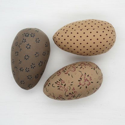 Three decorative eggs with floral and star patterns on a white background