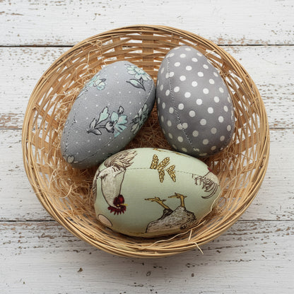 Decorative fabric egg bowl fillers in a wicker basket on a white background