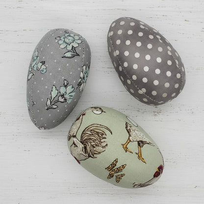 Three fabric-covered eggs with different patterns on a white background