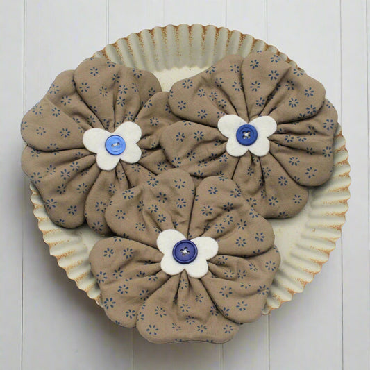 Fabric flower bowl fillers sewn from tan print fabric with blue buttons