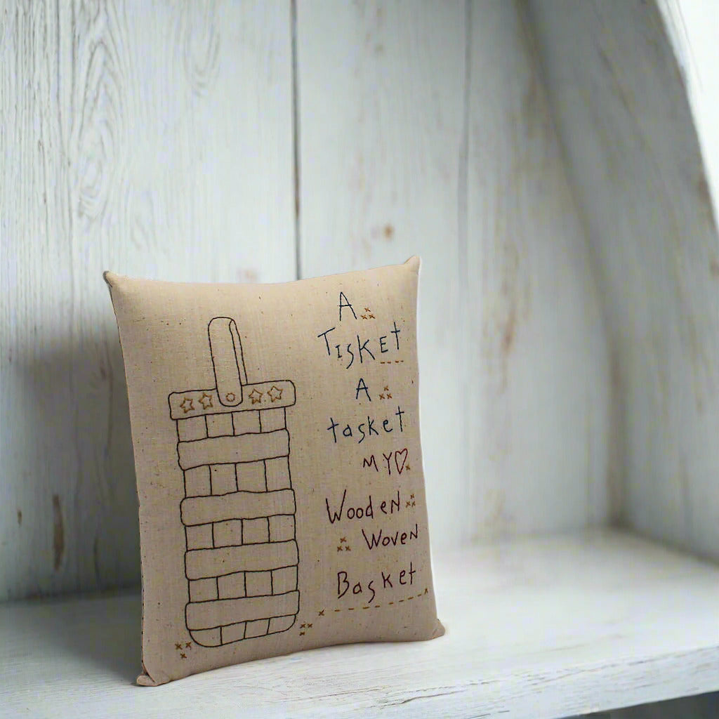 hand-stitched decorative pillow with a basket and poem, a tisket a tasket...