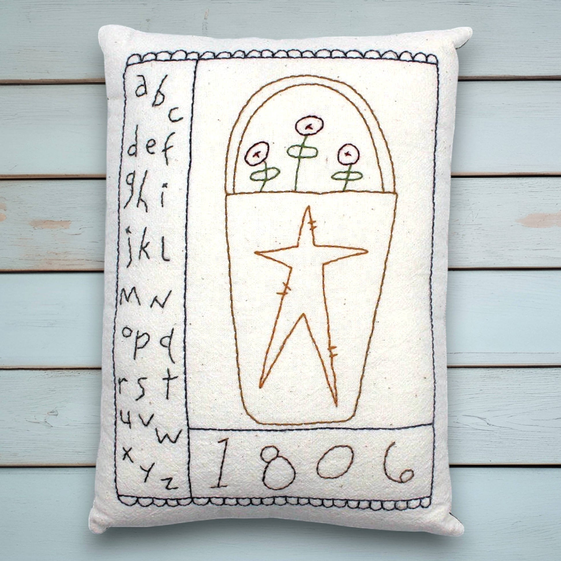 Decorative pillow with embroidered folk art design on a wooden surface