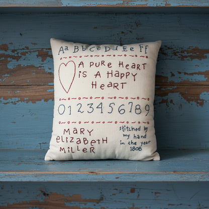 Hand-stitched decorative pillow with a happy heart sampler design