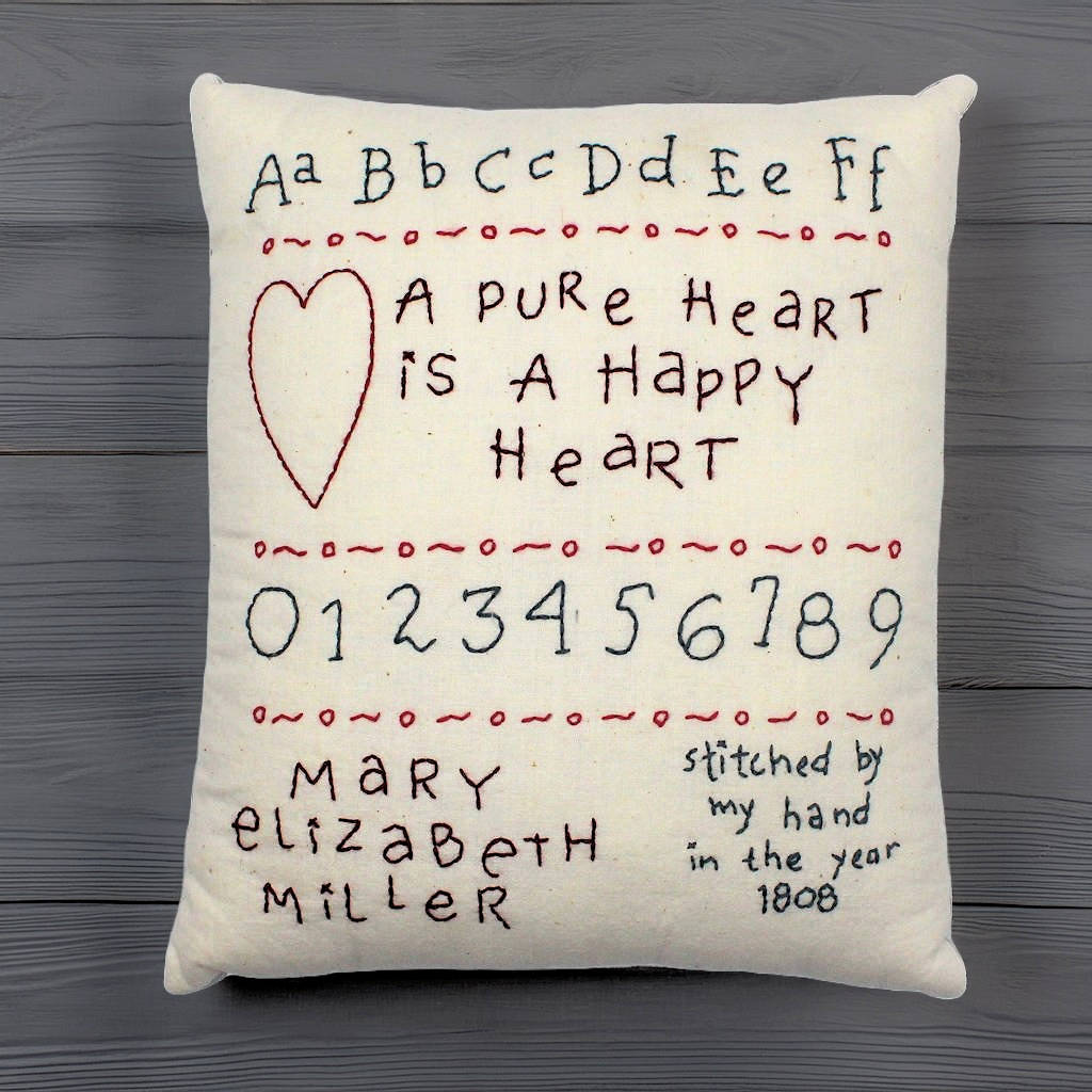 Hand-stitched decorative pillow with a happy heart sampler design