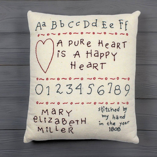 Hand-stitched decorative pillow with a happy heart sampler design