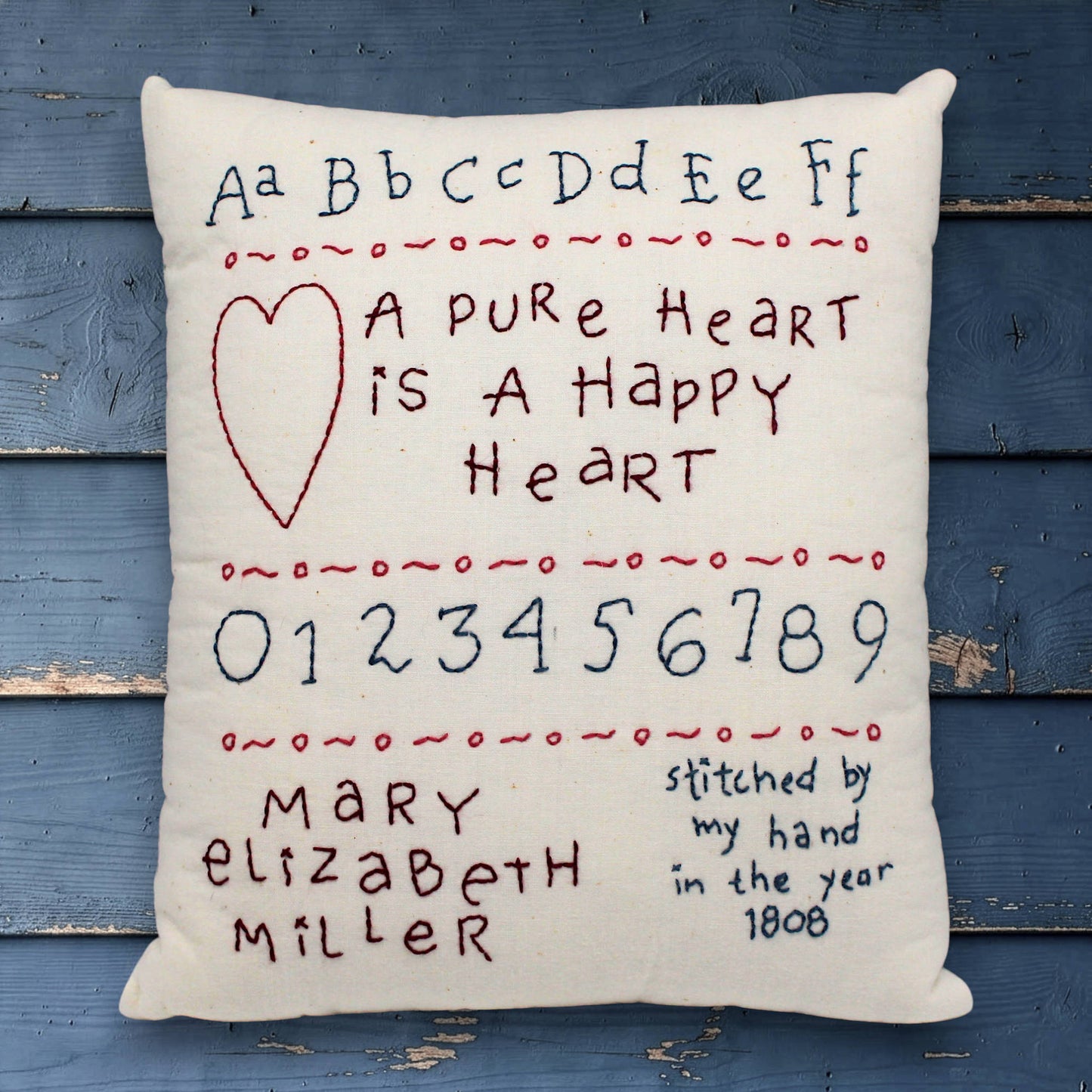 Decorative pillow with embroidered text and numbers on a wooden background