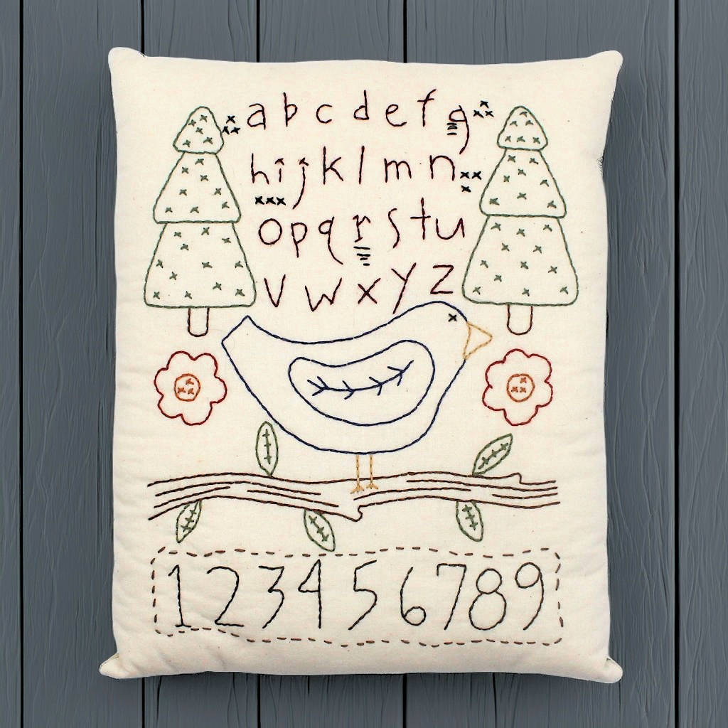 Hand-stitched decorative pillow with a bluebird sampler design