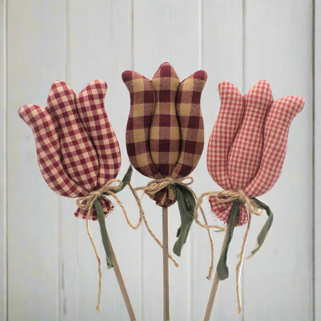 Three checkered tulip decorations on sticks against a light gray background