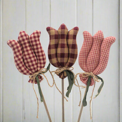 Three checkered tulip decorations on sticks against a light gray background