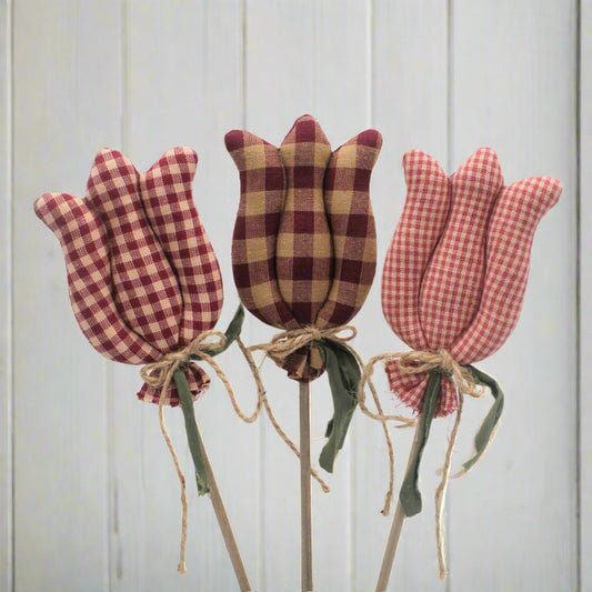 Three checkered tulip decorations on sticks against a light gray background