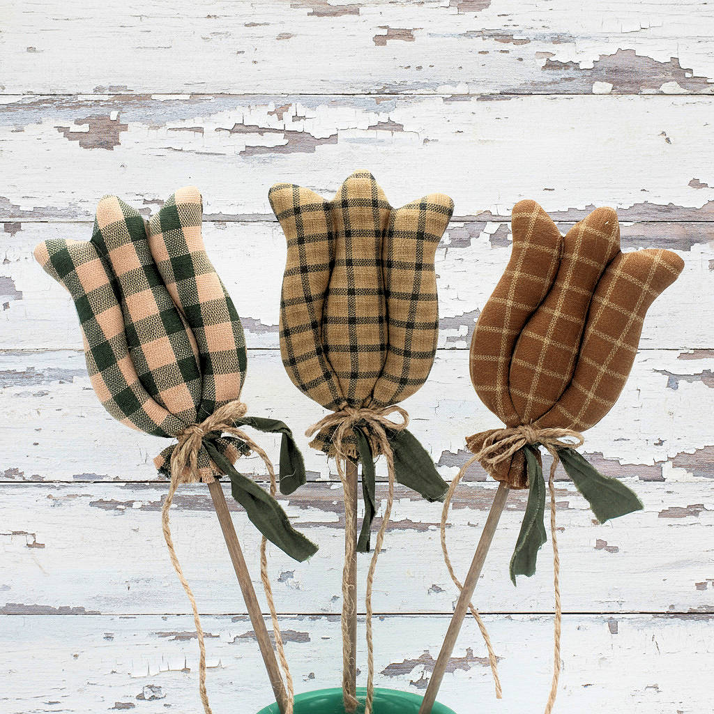 Three homespun fabric tulips tied with twine on a rustic wooden background