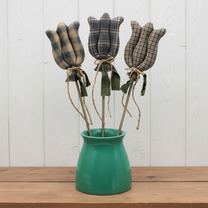 Three colonial blue fabric tulips in a green vase on a white background