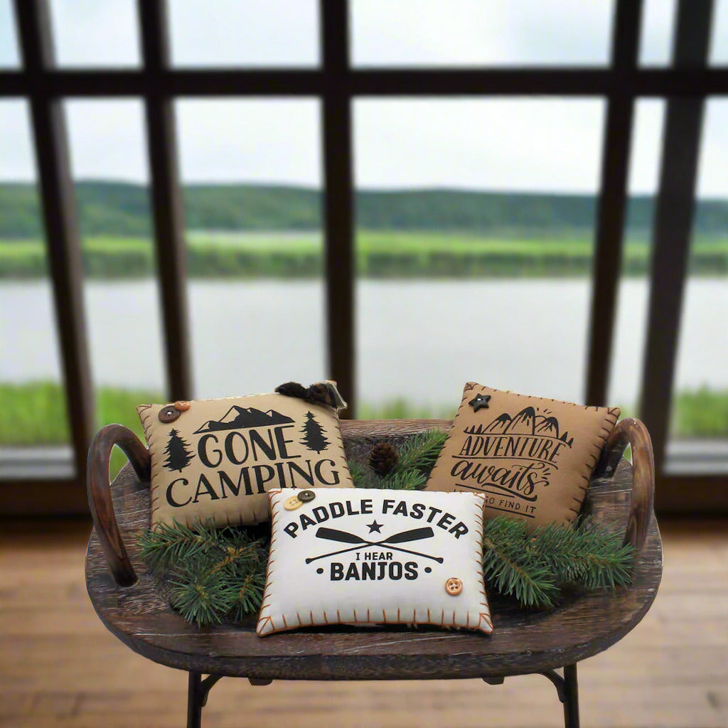 Three decorative pillows with text on a wooden tray