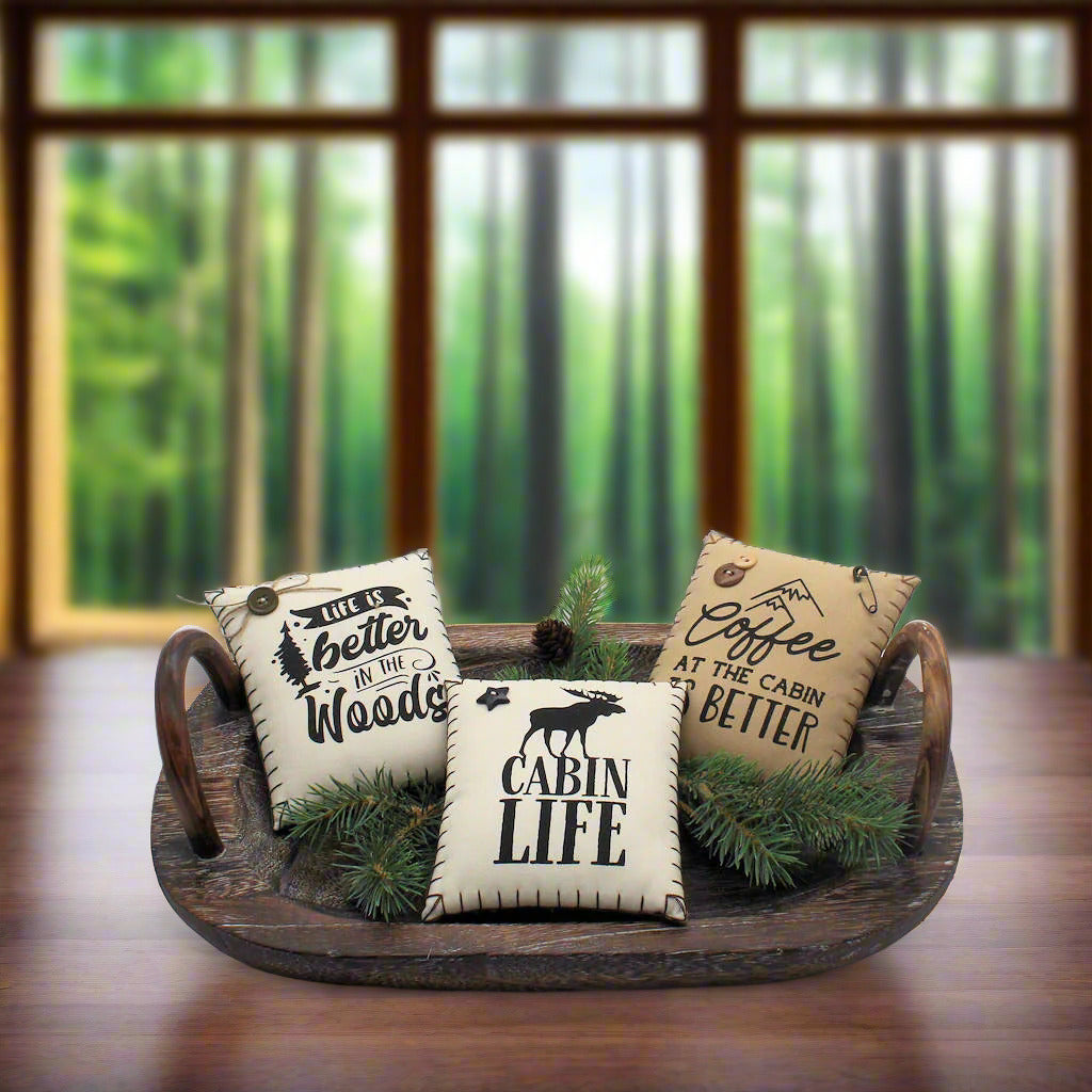 Three decorative pillows with text and a moose graphic on a wooden tray