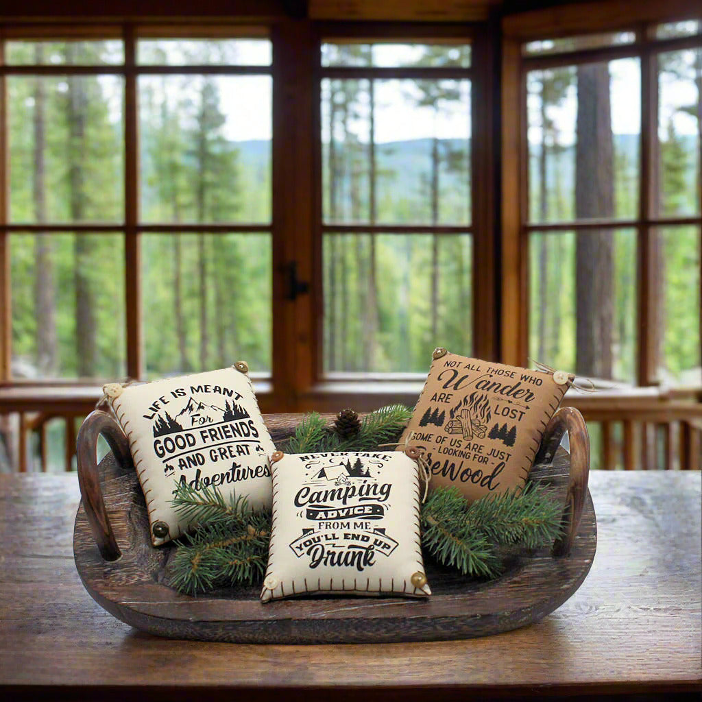 Decorative pillows with text and pinecones on a wooden tray
