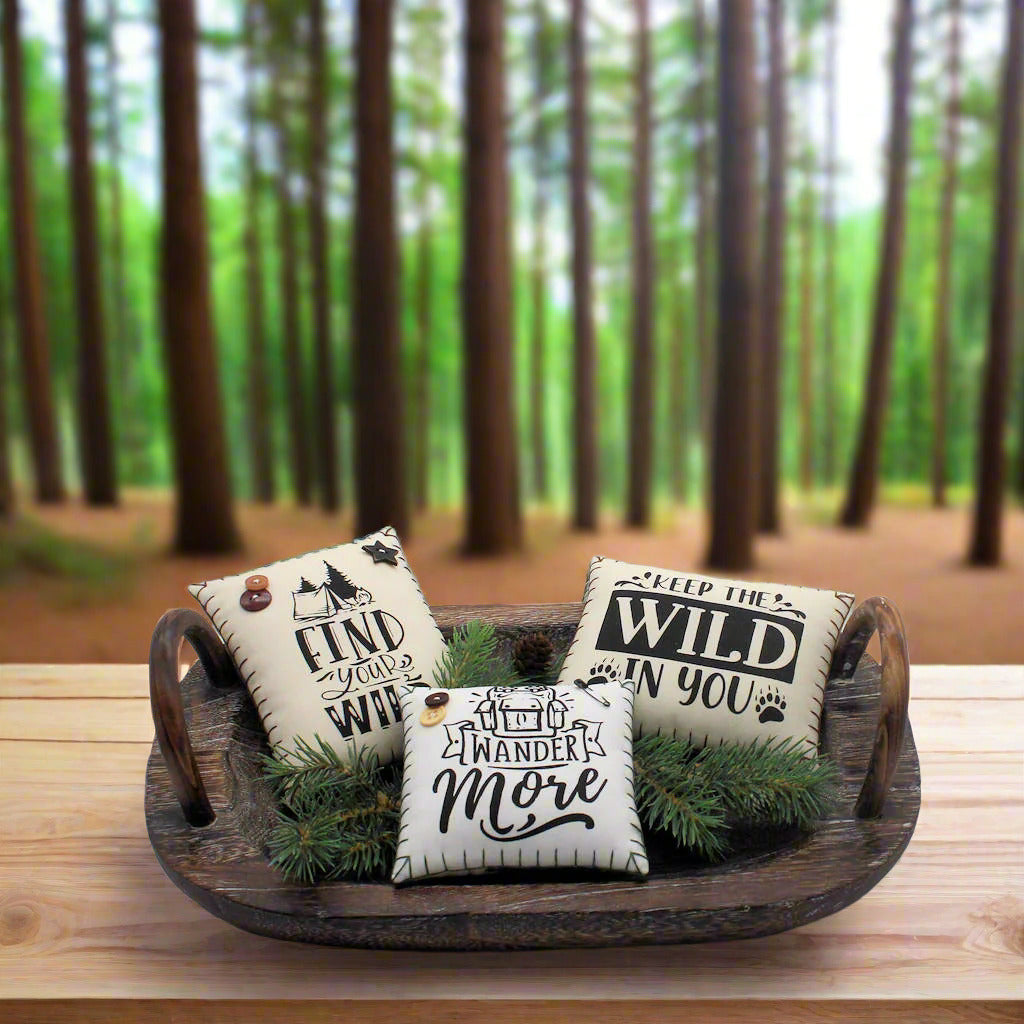 Three decorative pillows with motivational phrases on a wooden tray