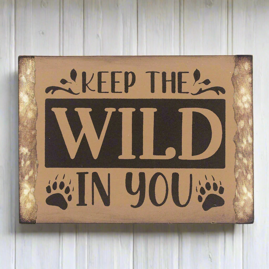 Small wooden camp or cabin sign that reads 'keep the wild in you'
