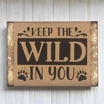 Small wooden camp or cabin sign that reads 'keep the wild in you'