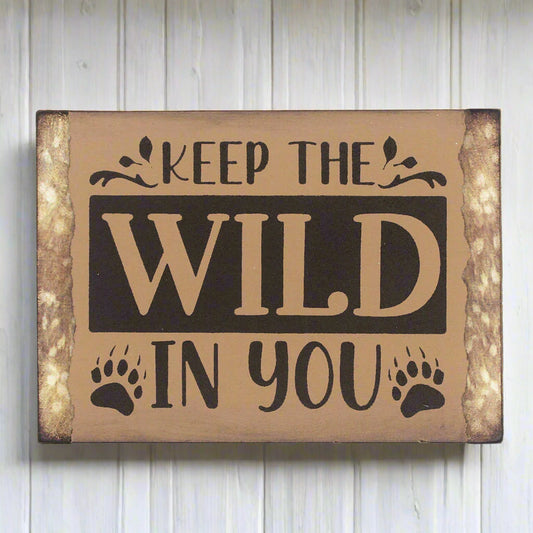 Small wooden camp or cabin sign that reads 'keep the wild in you'