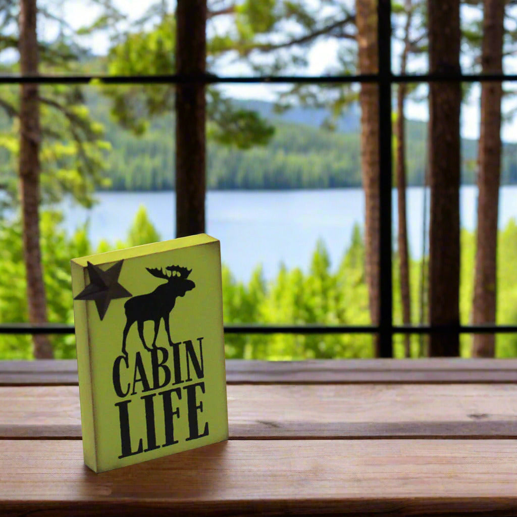 Green wooden sign with 'Cabin Life' and a moose design