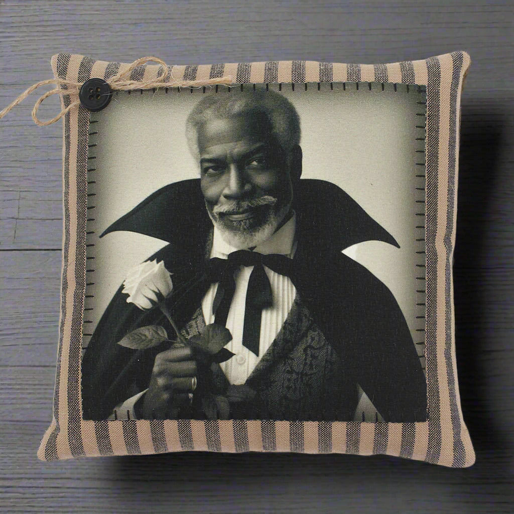 Decorative pillow with a black and white portrait of a handsome vampire holding a flower, framed by striped fabric.