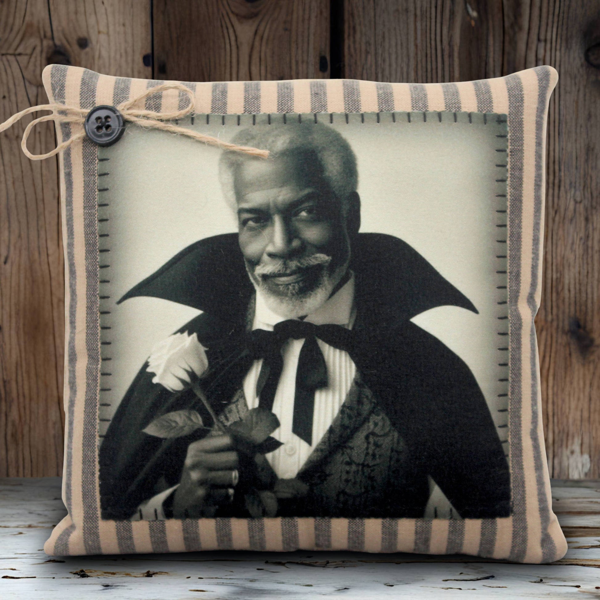 Decorative pillow with a black and white portrait of a handsome vampire holding a flower, framed by striped fabric.