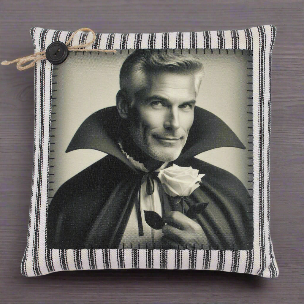 Pillow with a black and white print of a handsome vampire in a cape holding a rose, on a striped pillow cover.