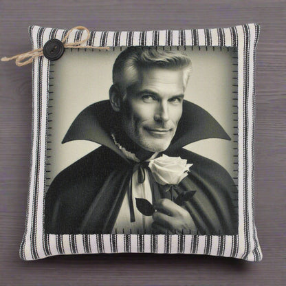 Pillow with a black and white print of a handsome vampire in a cape holding a rose, on a striped pillow cover.