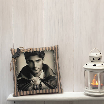 Decorative pillow with a portrait and striped border on a shelf next to a lantern.