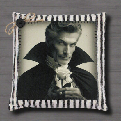 Decorative pillow with a black and white portrait of a handsome vampire in a cape holding a rose, framed by a striped border.