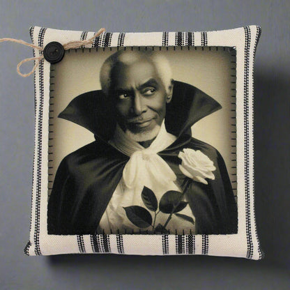 Pillow with a vintage-style print of a handsome vampire in a dark robe holding a white rose on a striped background.