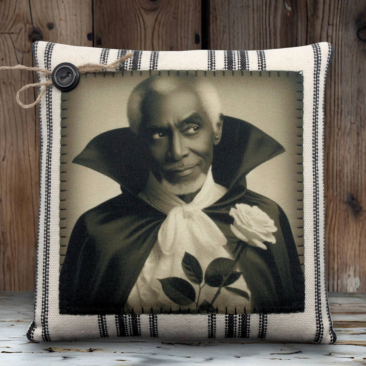 Pillow with a vintage-style print of a handsome vampire in a dark robe holding a white rose on a striped background.