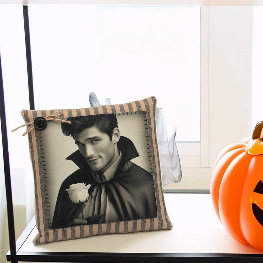 Decorative pillow with a black and white image of a handsome young vampire in a costume, next to a small pumpkin.