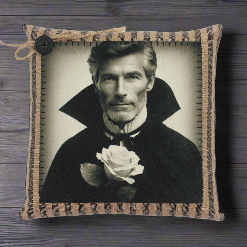 Decorative pillow with a black and white portrait of a handsome vampire holding a rose, framed by striped fabric.