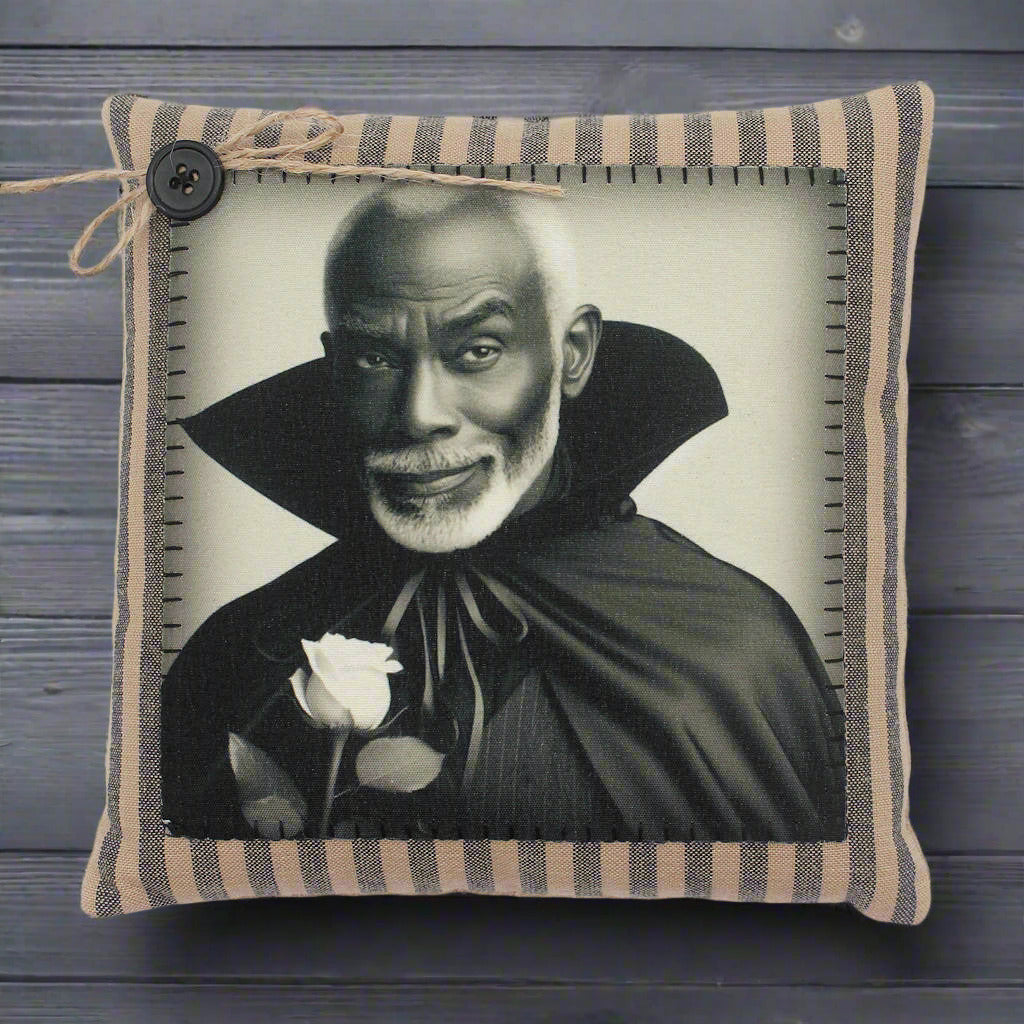 Pillow with a black and white portrait of a handsome vampire in a cape holding a rose, framed by striped fabric.