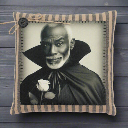 Pillow with a black and white portrait of a handsome vampire in a cape holding a rose, framed by striped fabric.