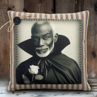 Pillow with a black and white portrait of a handsome vampire in a cape holding a rose, framed by striped fabric.