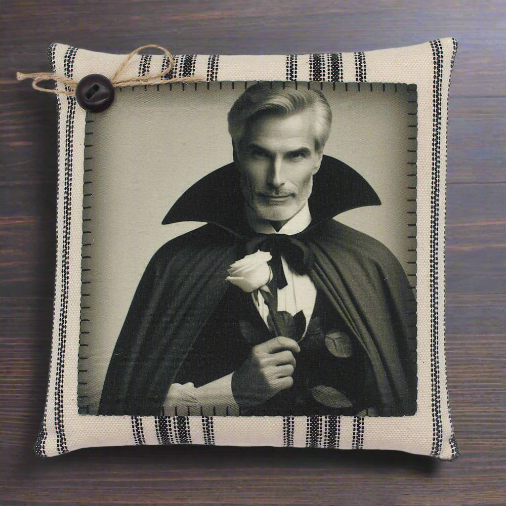Decorative pillow with a portrait of a handsome vampire in a cape holding a rose, framed by striped fabric.