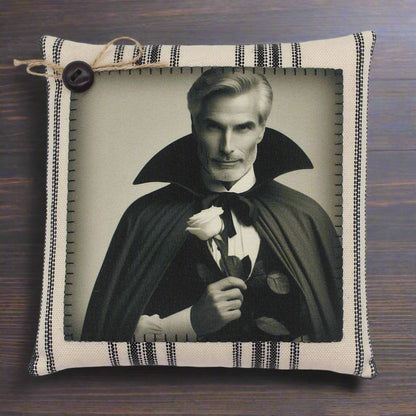 Decorative pillow with a portrait of a handsome vampire in a cape holding a rose, framed by striped fabric.