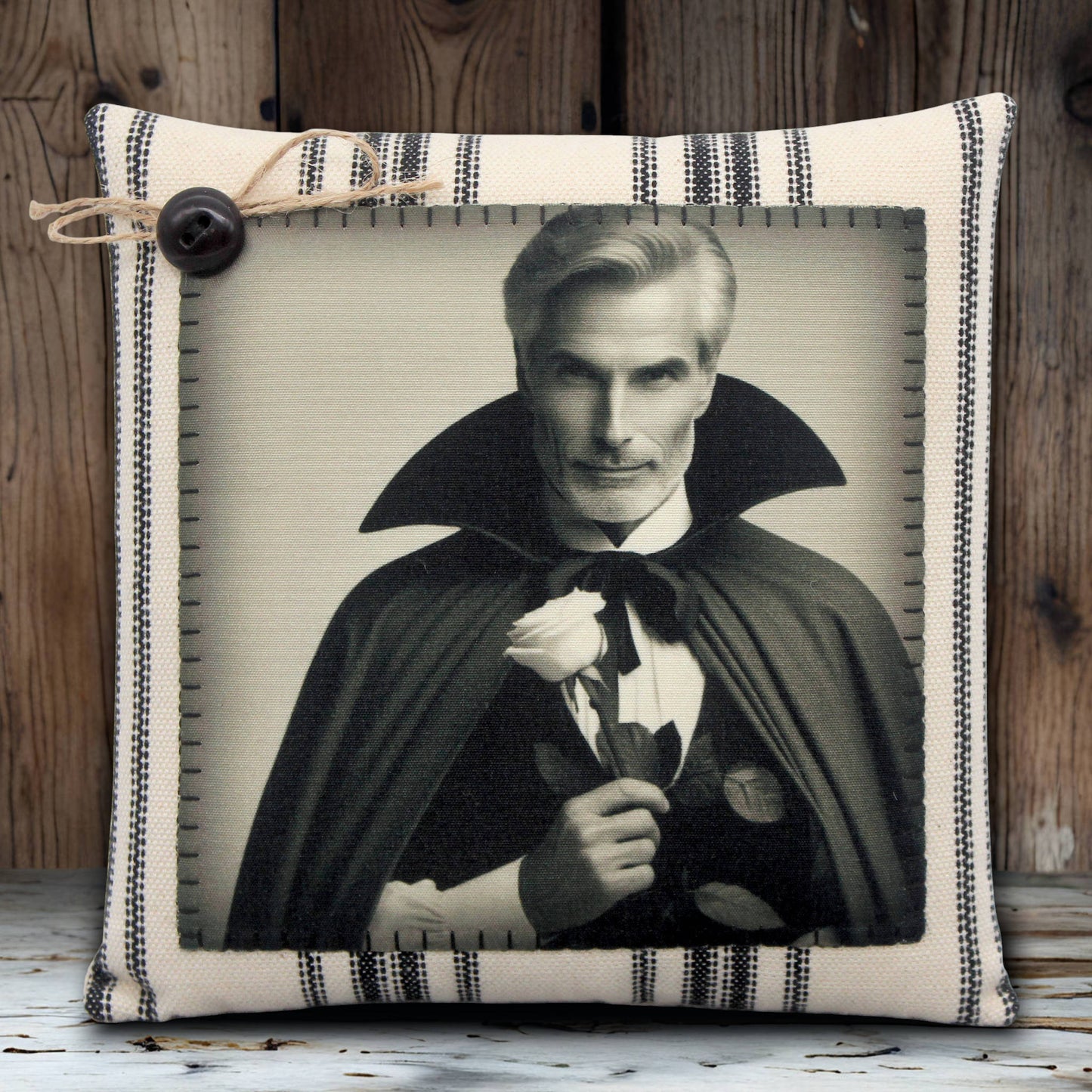Decorative pillow with a portrait of a handsome vampire in a cape holding a rose, framed by striped fabric.